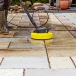 Cleaning stone slabs on patio with the high-pressure cleaner. Pe